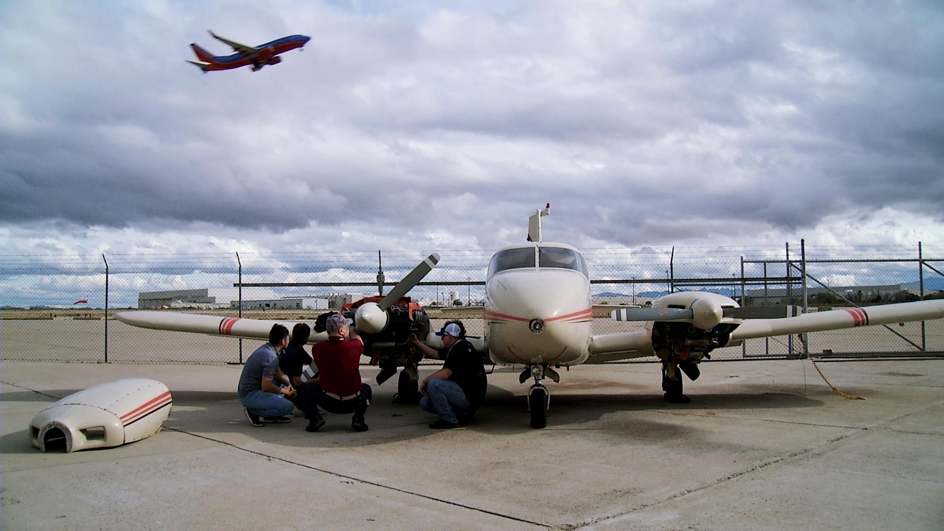 Students enrolled in Pima Community College's Aviation Technology Program do maintenance on a plane as a commercial aircraft takes off from the nearby Tucson International Airport on Feb. 4, 2019. 