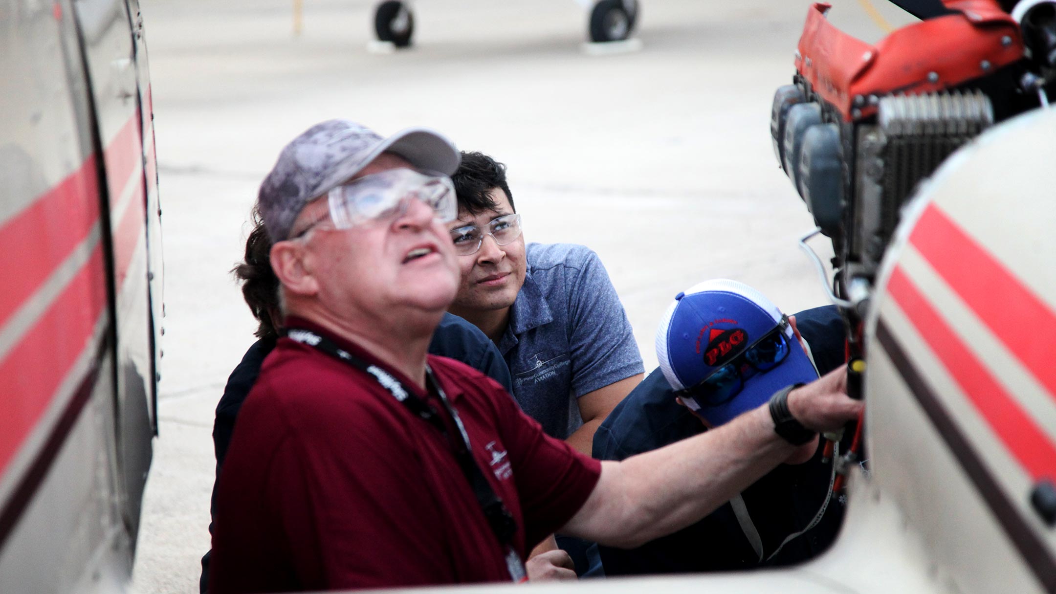 Students and an instructor at Pima Community College's aviation technology program watch a plane pass above as they perform maintenance on a small aircraft at the college's facility near Tucson International Airport on Feb. 4, 2019. 