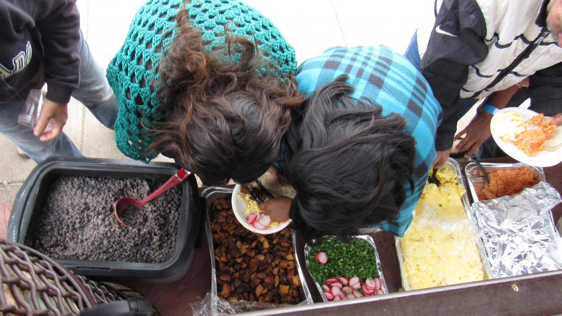 Newly released migrants get food from a buffet set up by aid workers on the bench of a Phoenix-area bus stop.