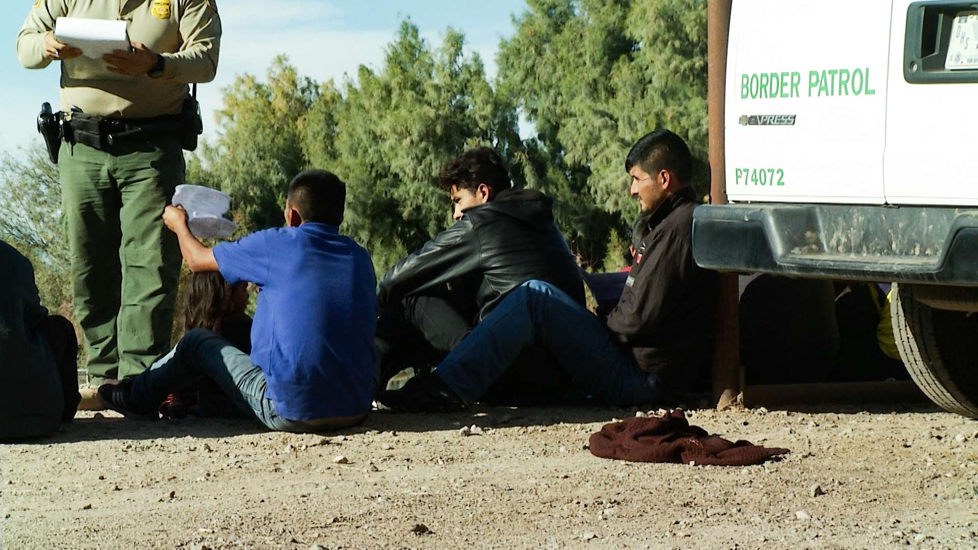 A group of men, women and children prepare their documents after approaching and surrendering to Border Patrol in the Yuma Sector, 2019.