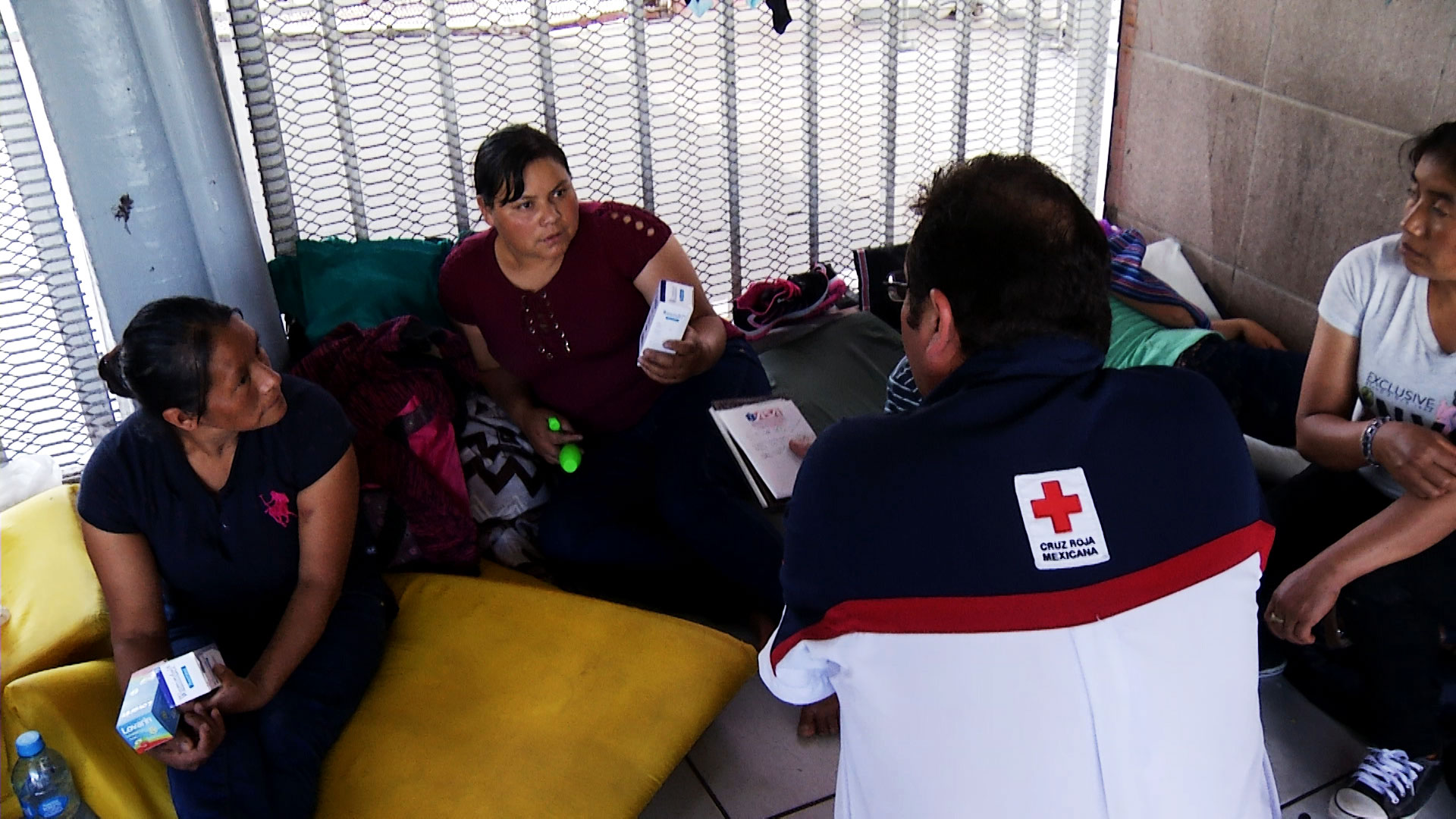 A Mexican Red Cross volunteer offers medicine to a woman waiting to make a request for asylum outside the port of entry in Nogales, Sonora, on Sept. 4, 2018.