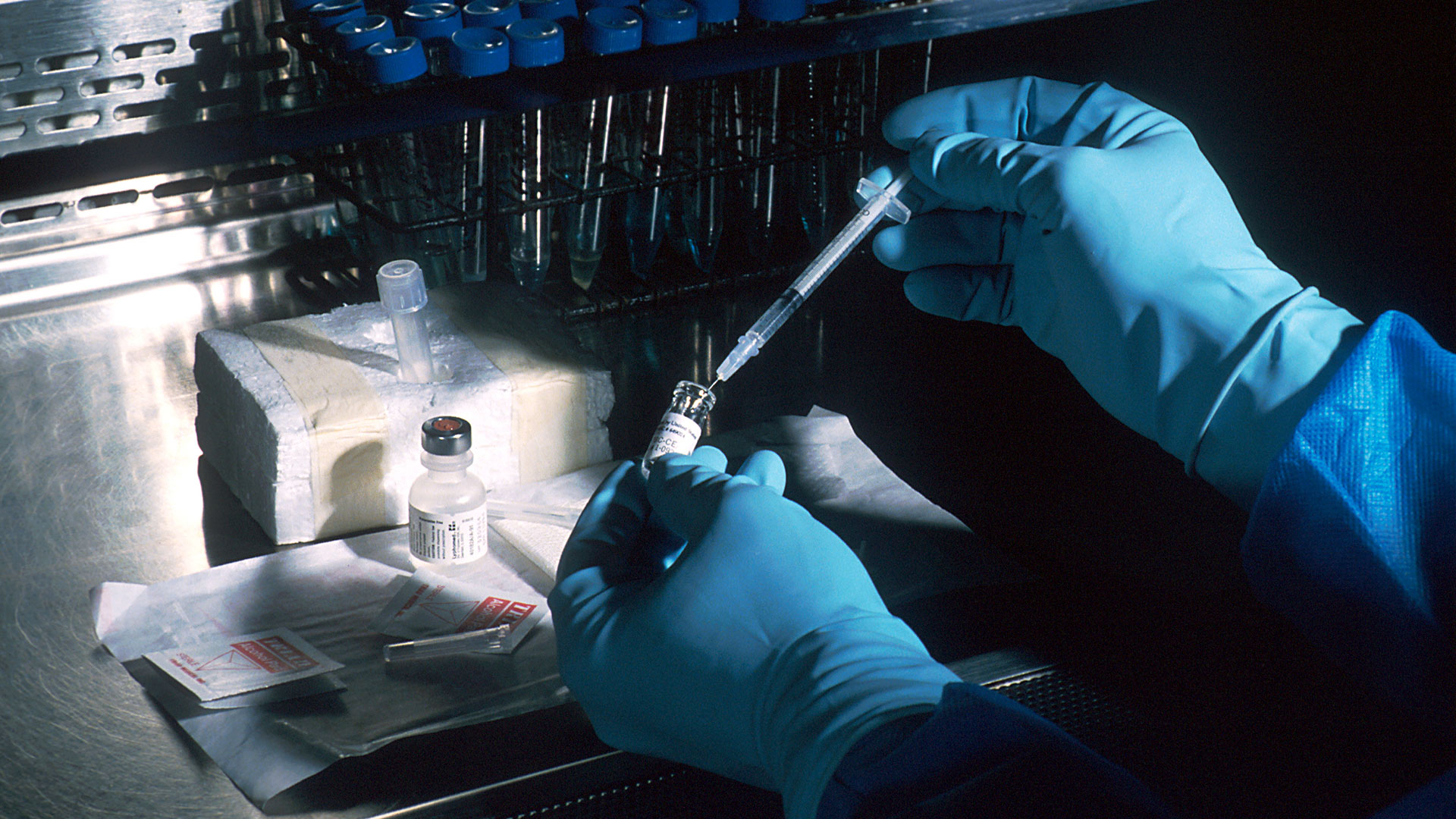 Hands of a scientist, under a sterile hood, preparing a vaccine.