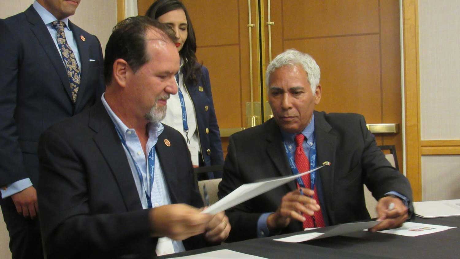 Sonora's Luis Gonzalez (left) hands a signed copy of a memorandum of understanding to Arizona's Matthew Earl Jones on the first day of meetings for the Arizona-Mexico Commission.