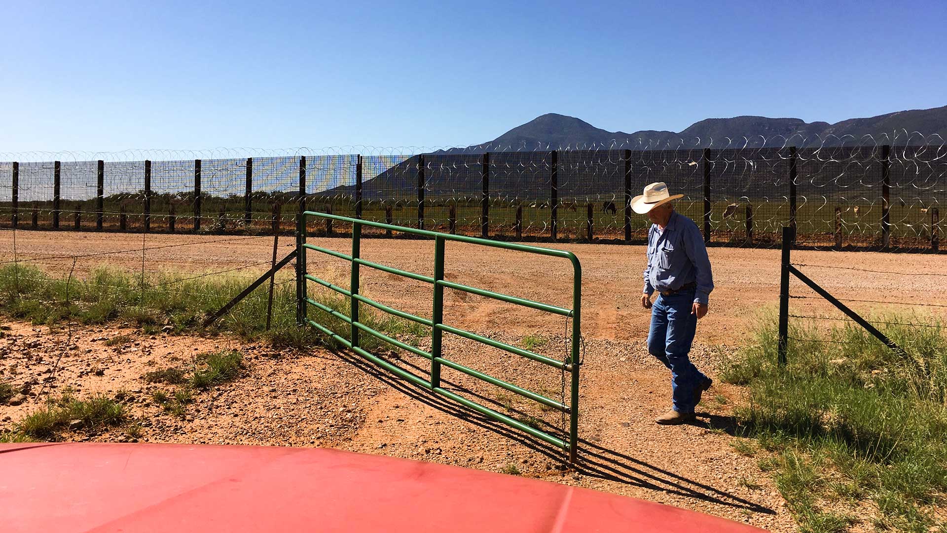 Rancher John Ladd opens a gate on his property where it meets the U.S.-Mexico border fence.