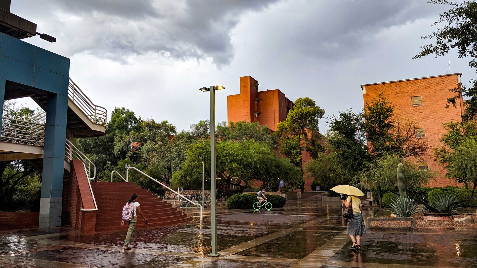 People on the University of Arizona campus take advantage of a lull in a summer rain storm to get to where they're going, Aug. 28, 2019.