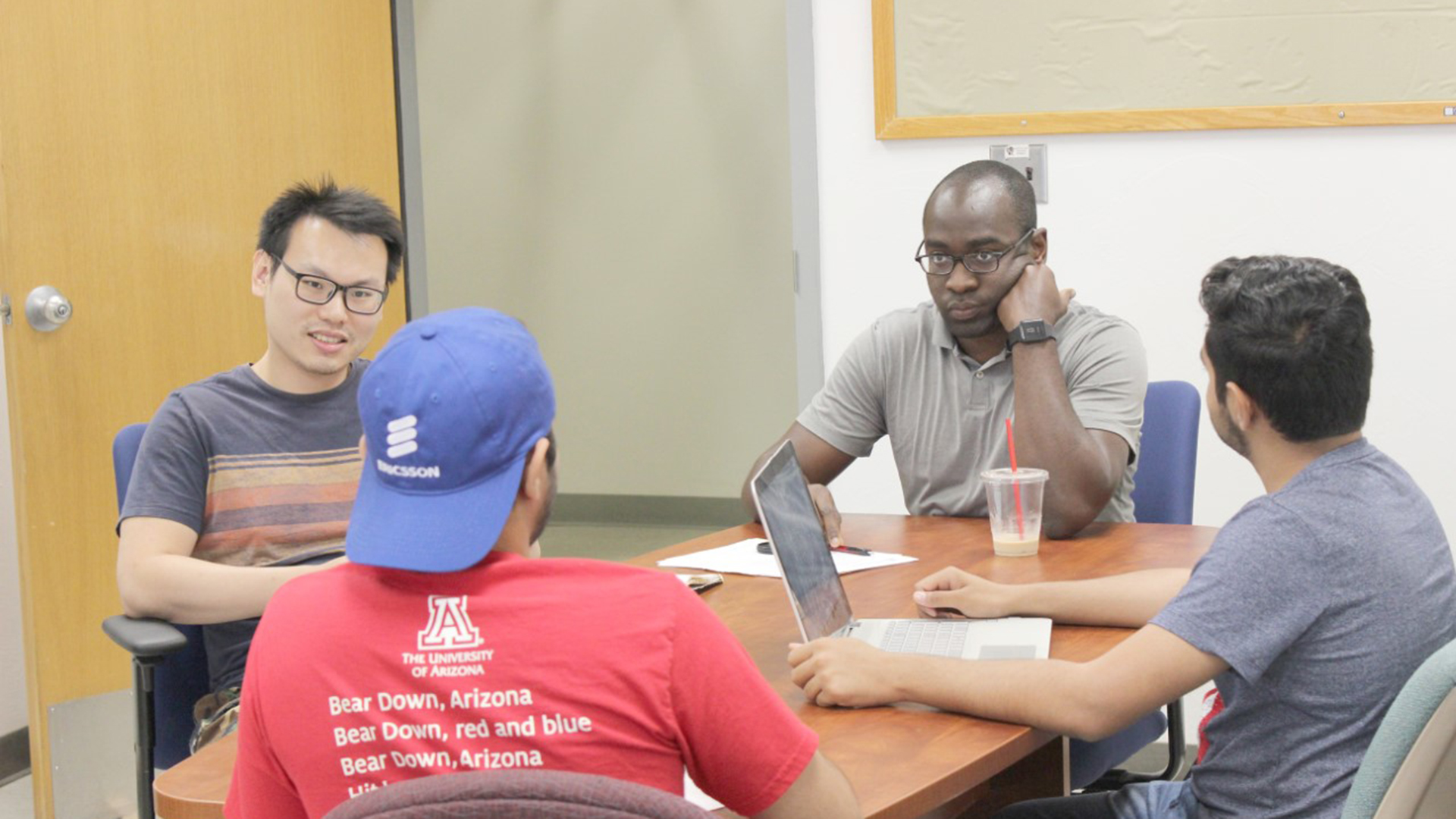 Tosi Adegbija, center, listens as UA students discuss computer engineering proposals.