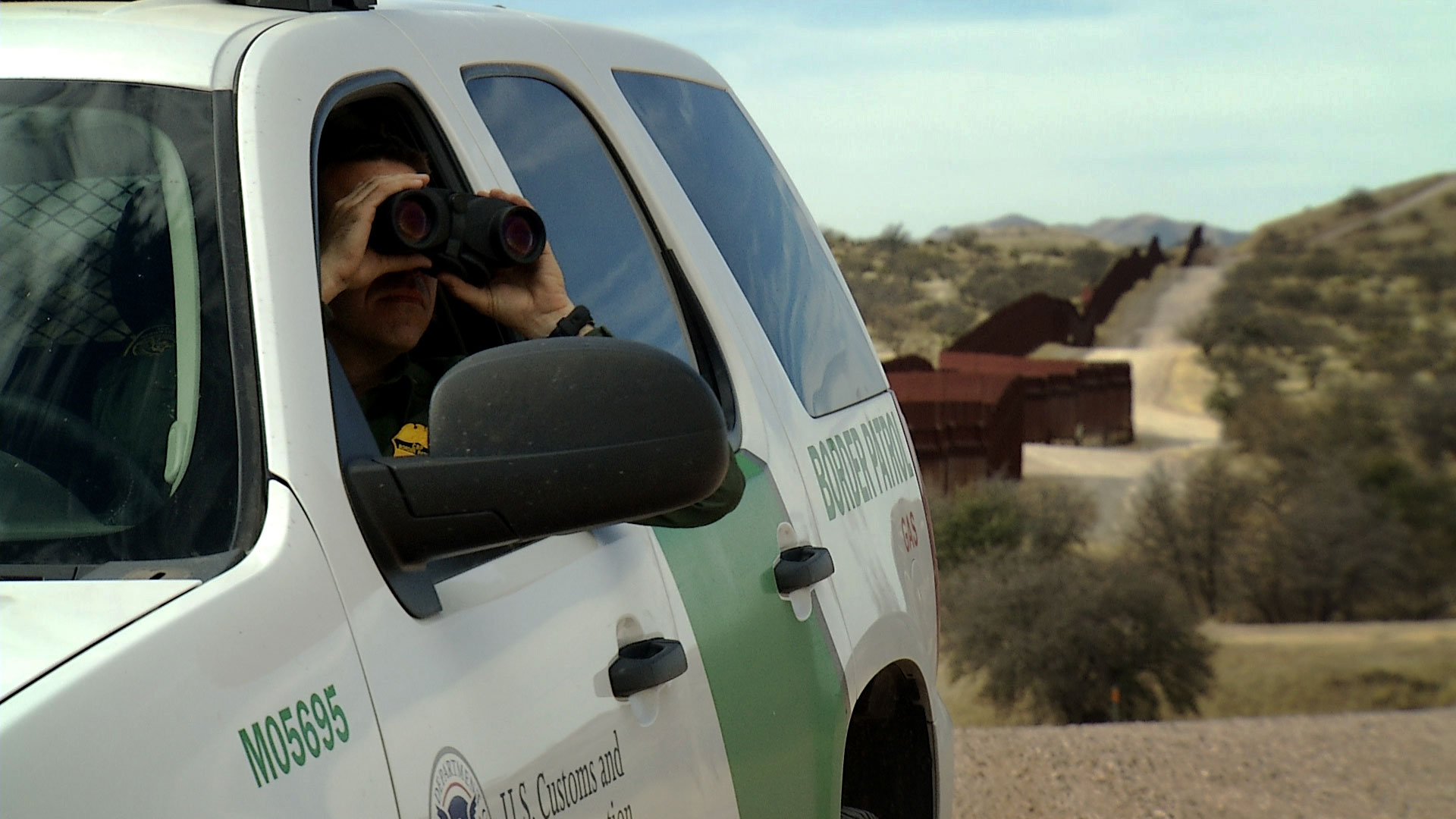 File image of a Border Patrol agent using binoculars to surveil an area just north of Arizona's border with Mexico. 