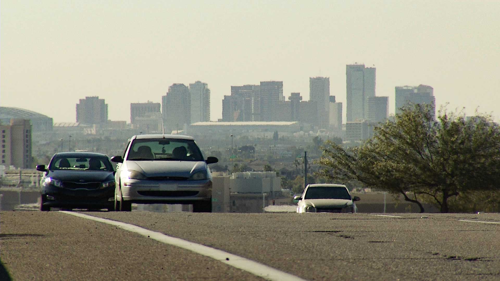 Cars driving with downtown Phoenix in the background