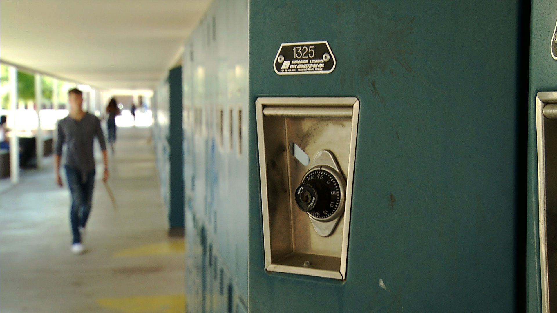 A locker door is visible in the foreground as a student walks in the distance at Marana High School in September 2019. 