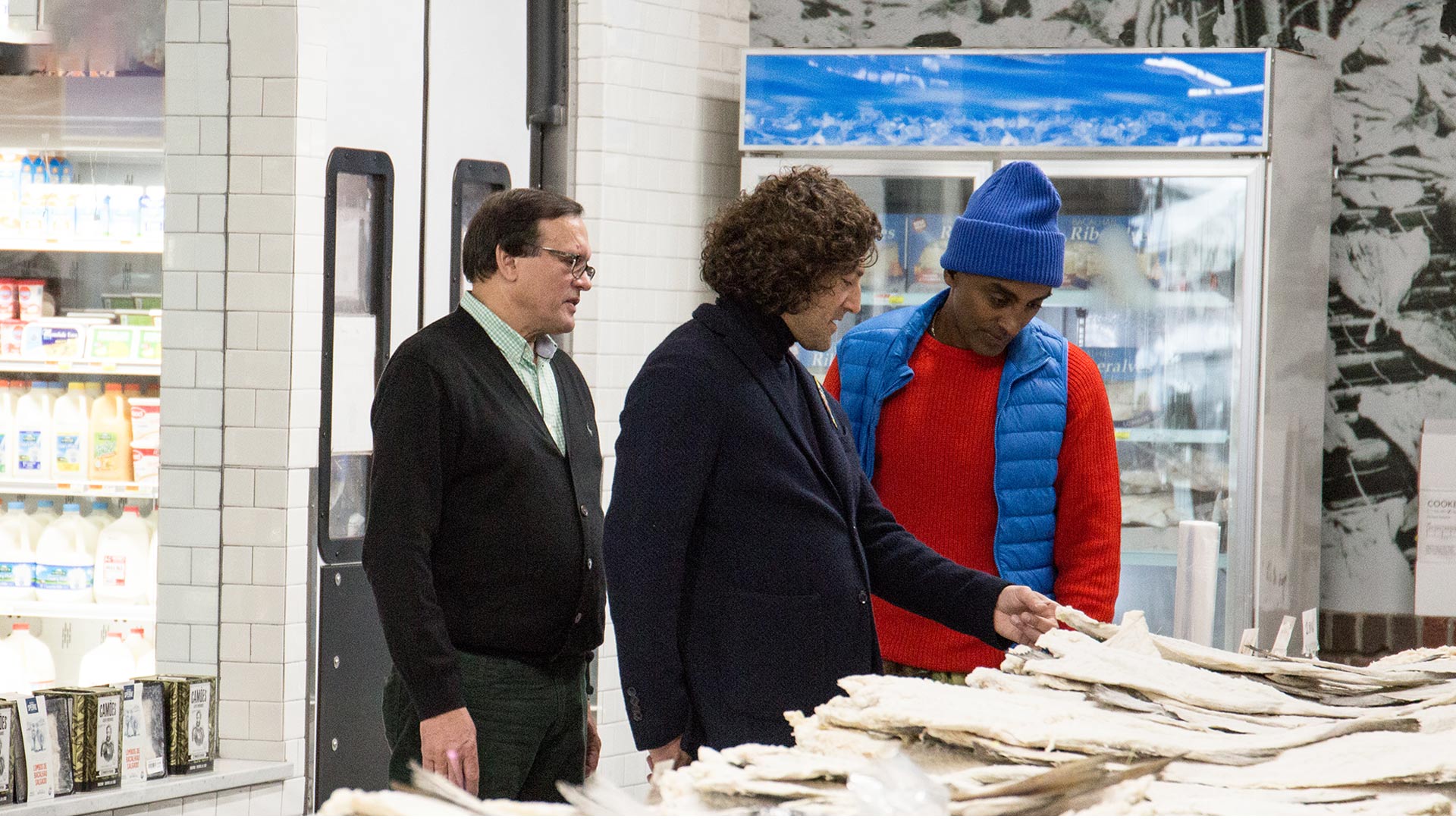 Father and son Fernando and Michael Benevides, owners of Portugalia Marketplace, show Chef Marcus Samuelsson their bacalhau storehouse.