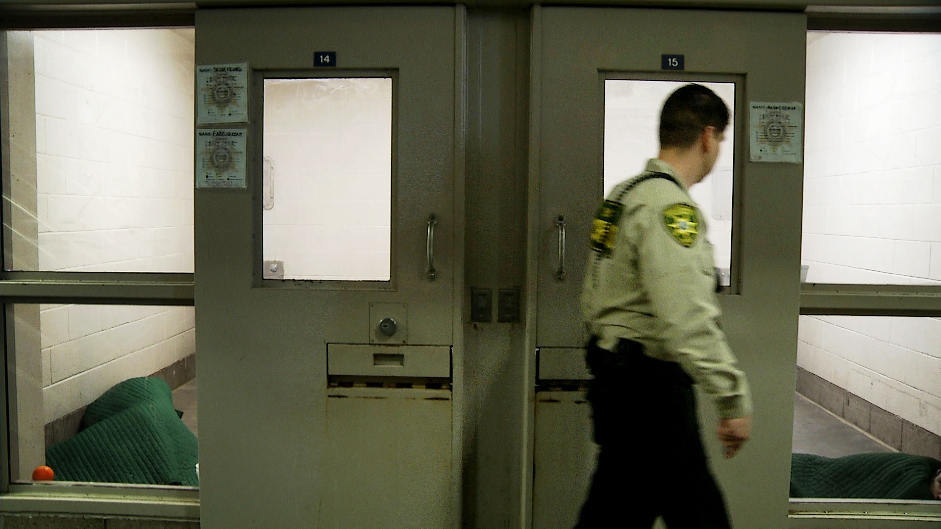 A Pima County correctional officer glances inside a cell at the county jail. 