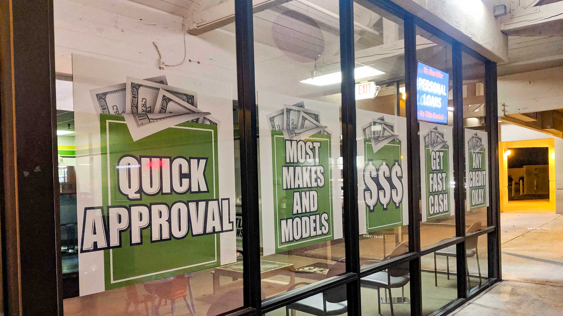 A storefront window advertising auto title loans in Tucson, July 2019.
