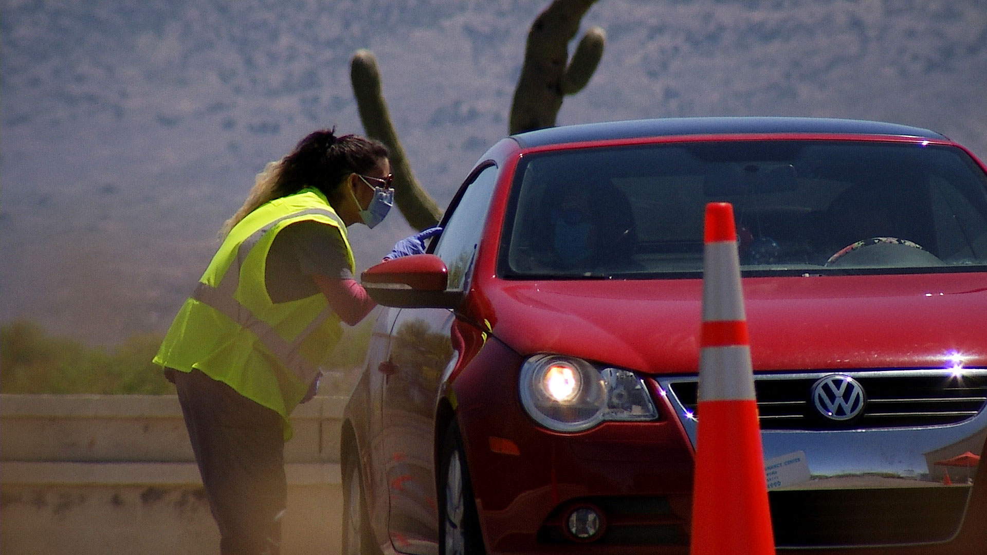 A woman speaks to someone in a vehicle seeking a COVID-19 test at a drive-thru testing site set up at Walgreens in Tucson on April 21, 2020. 