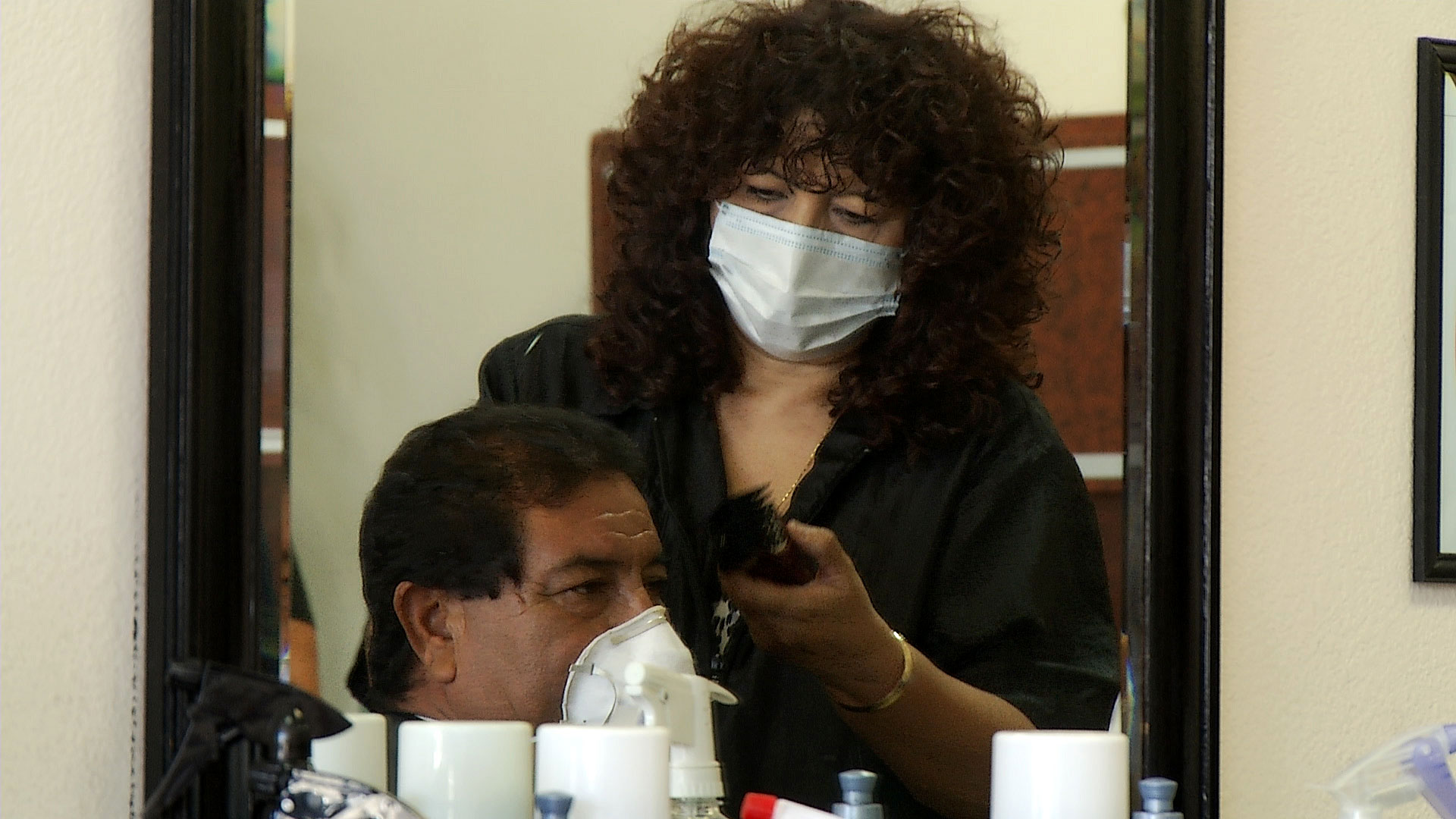 Both a customer and stylists wear face masks during a hair cut at Eclips Cuts Salon in Tucson on May 12, 2020. The salon reopened when Arizona eased COVID-19-related restrictions that had ordered barbers and salons to close. 