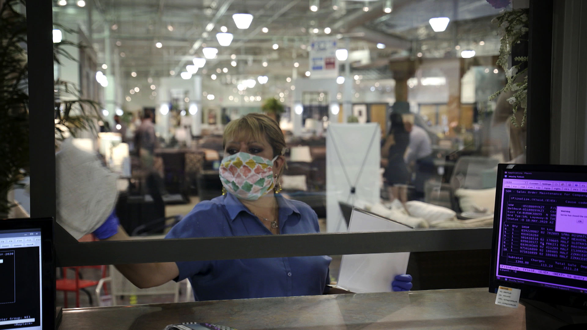 An employee at Sam Levitz sanitizes a plexiglass shield at the company's warehouse on May 19, 2020.