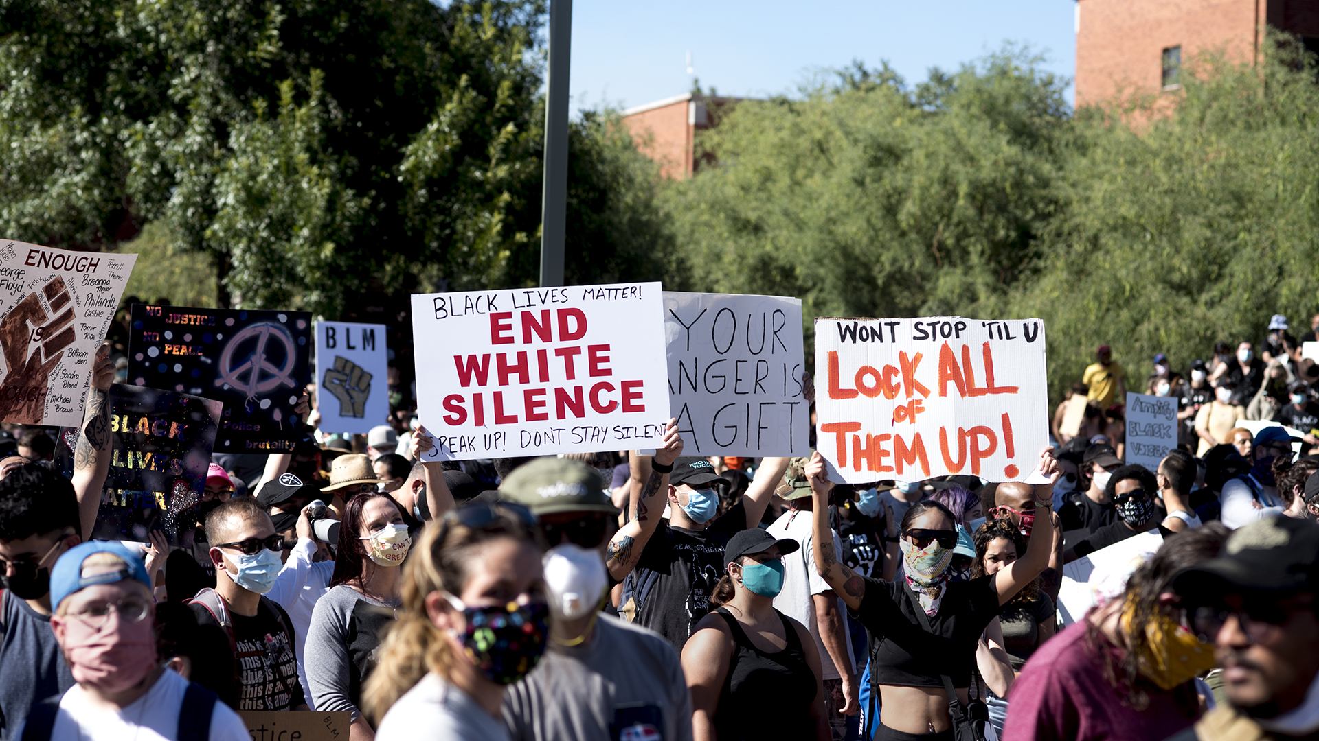 Demonstrators hold up signs recognizing George Floyd and condemning police brutality during and Black Lives Matter Tucson event on June 6, 2020.  
