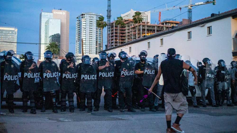 A protester approaches a line of police officers in downtown Phoenix on Sunday, May 31, before the imposition of a statewide curfew to rein in protests over police violence.
