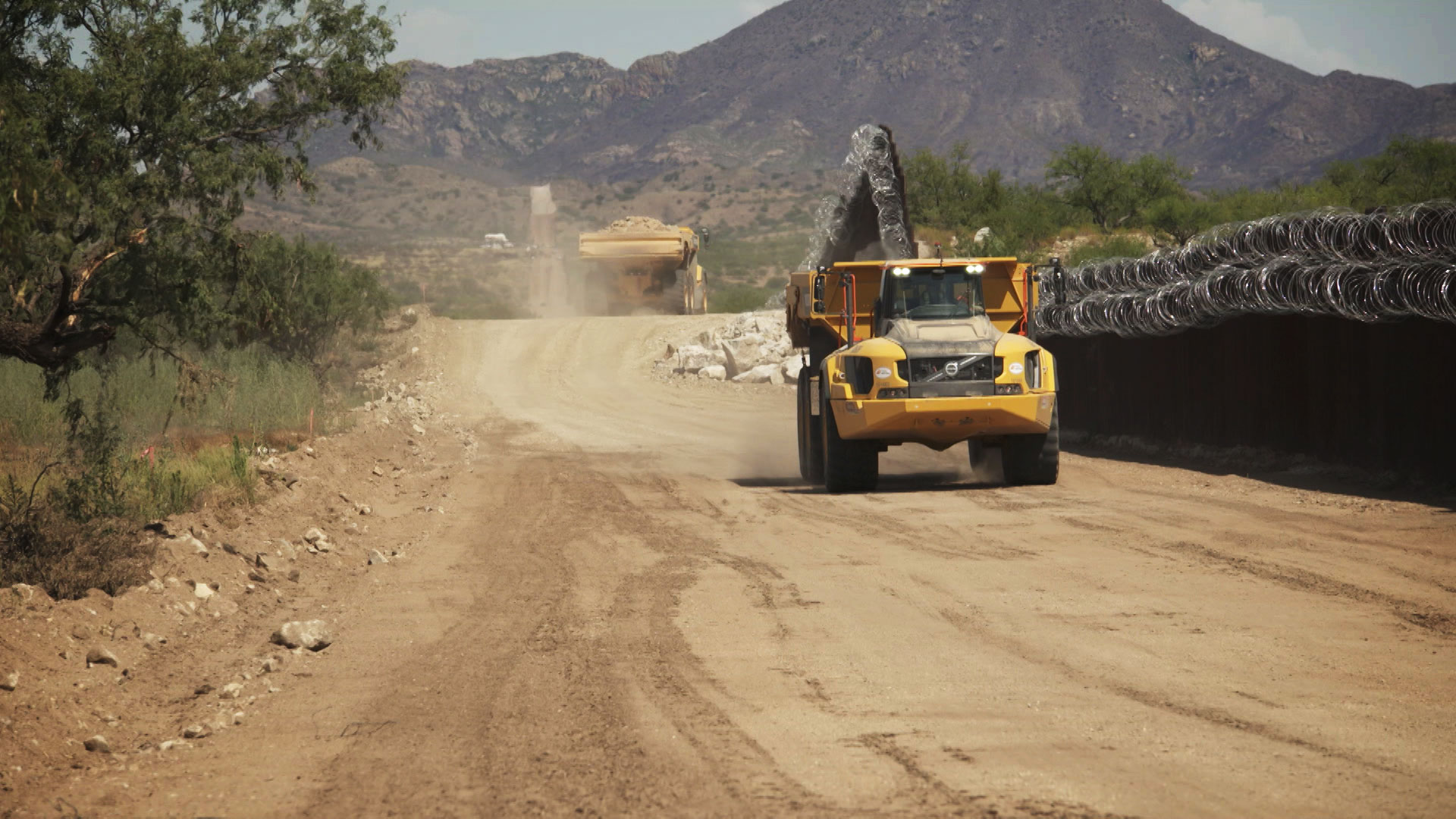 Construction trucks drive along the border wall in Sasabe on July 13, 2020. 