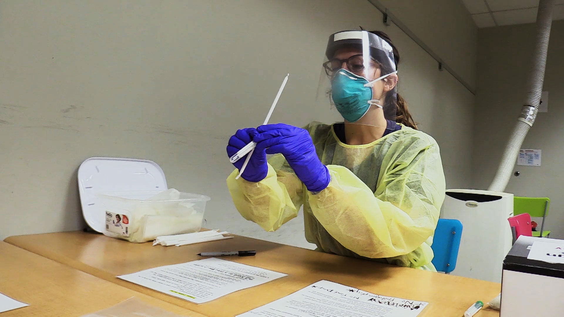 A health care worker handles supplies needed to collect saliva to test for COVID-19 as part of Arizona State University's testing initiative. 