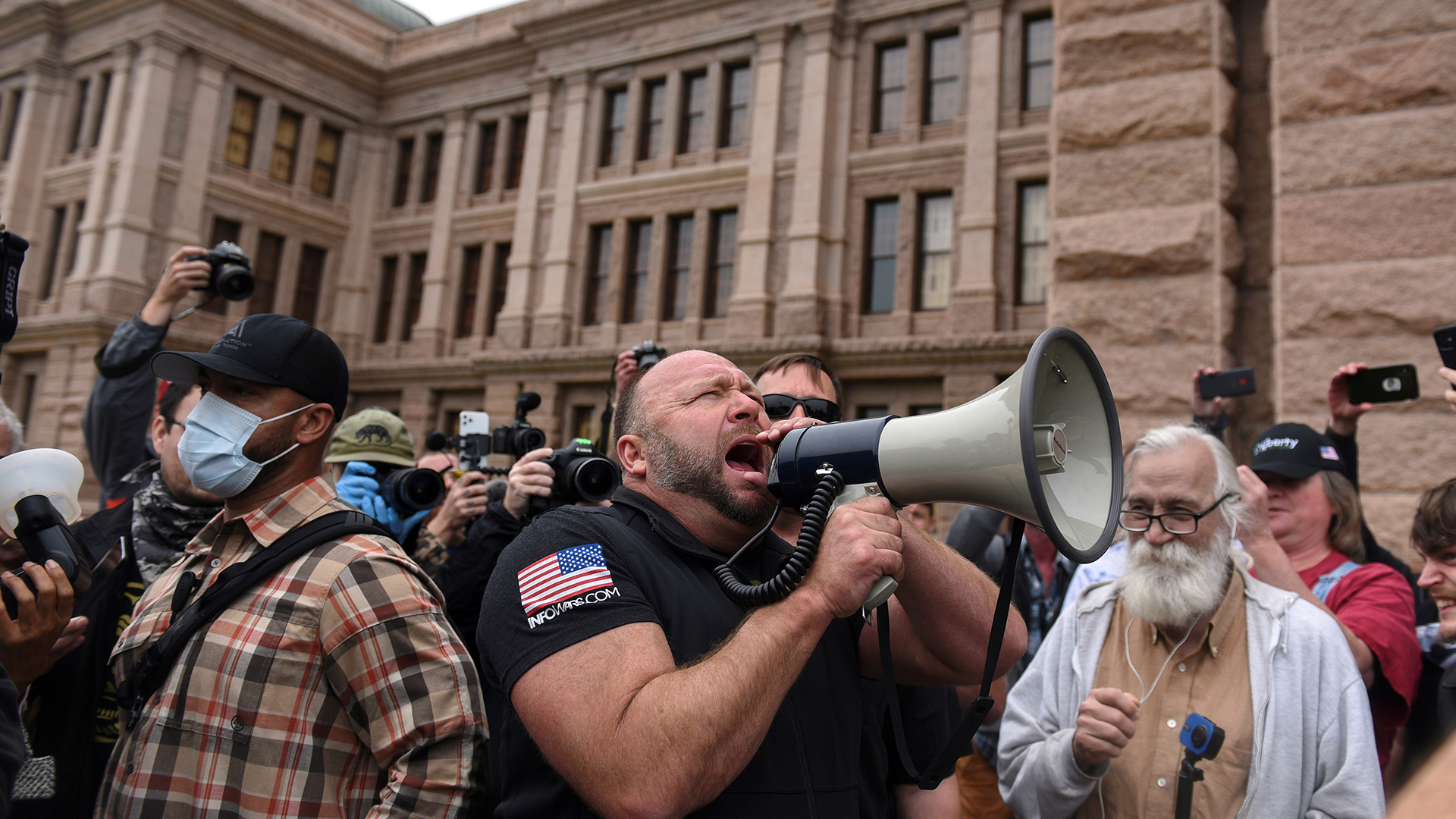 Alex Jones screams into a megaphone as protesters against the state's extended stay-at-home order to help slow the spread of the coronavirus disease (COVID-19) demonstrate at the Capitol building in Austin, Texas, U.S., April 18, 2020.