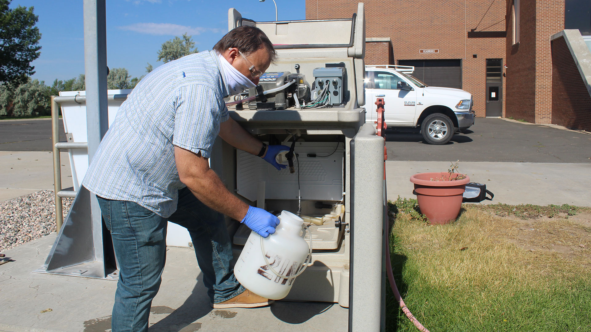 Jason Graham, director of wastewater plant operations with the city of Fort Collins, pulls a plastic jug from a sampling machine at the Drake Water Reclamation facility. 