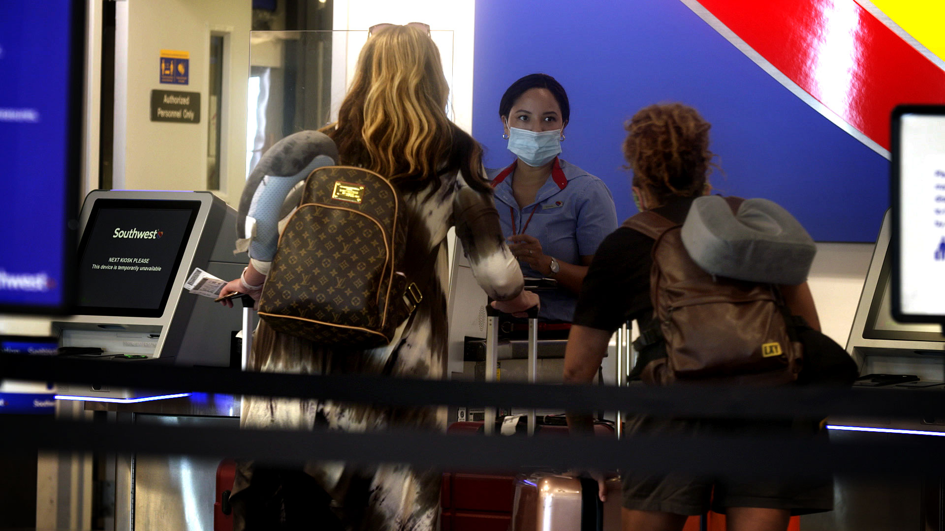 An employee for Southwest Airlines helps passengers at the ticket counter inside the Tucson International Airport on August 10, 2020.