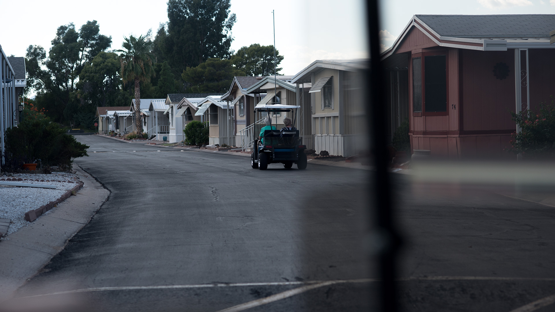 Pat Shoneck and Eileen Green ride in a golf cart at the Swan Lake Estates mobile home park, a 55+ park where Shoneck lives. 