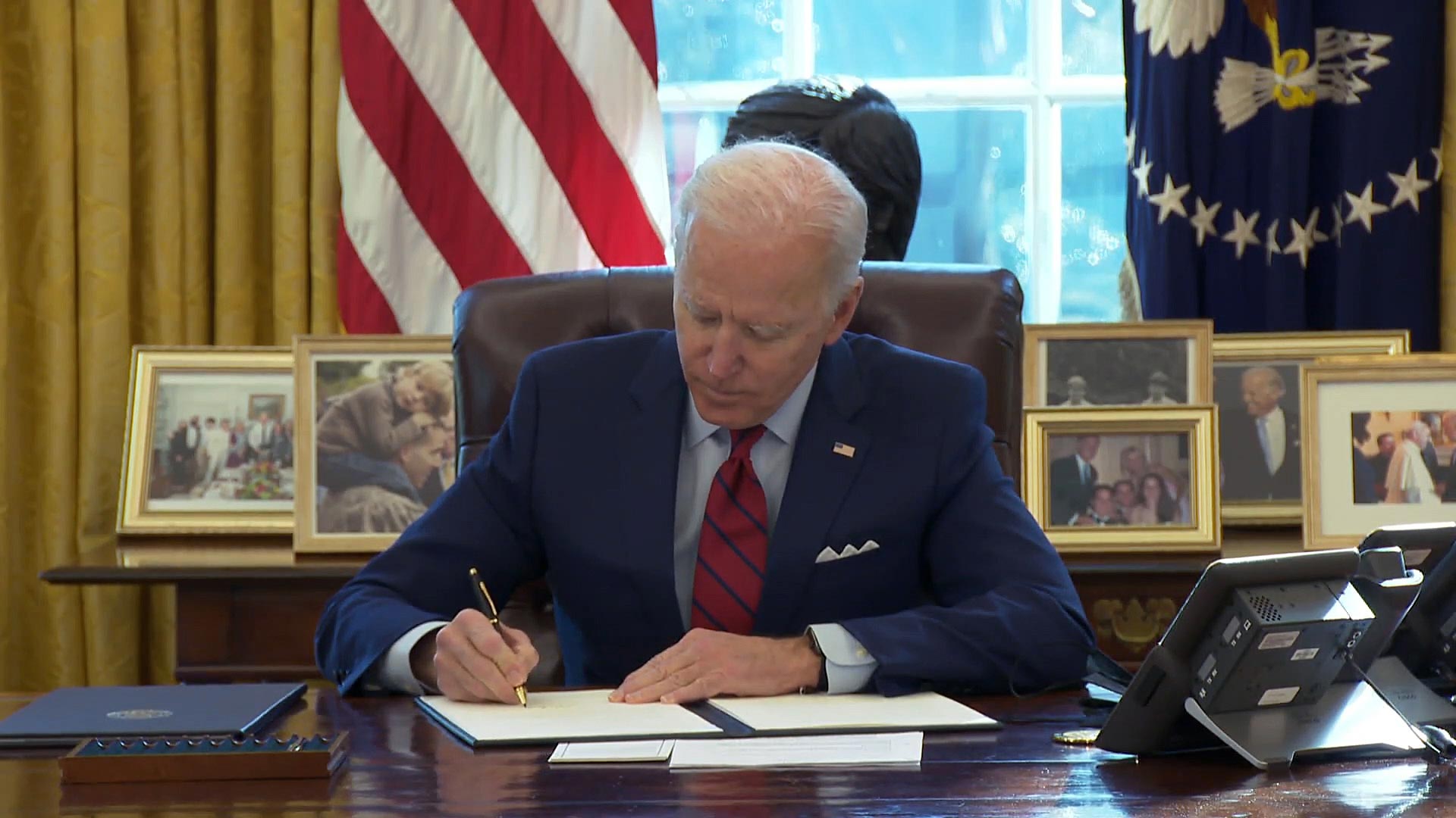 President Joe Biden signs executive orders at his desk in the Oval Office on Jan. 28, 2021. 