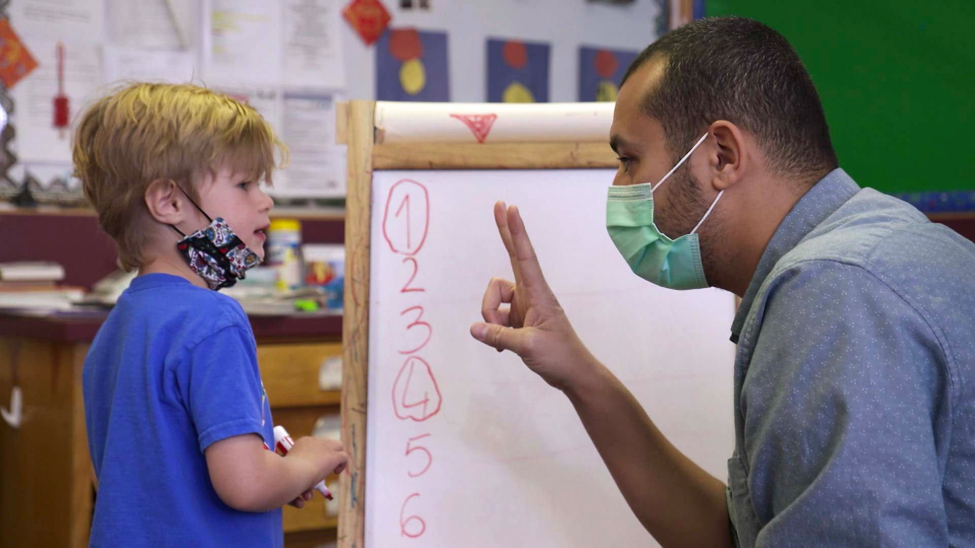 A masked teacher offers instruction to a student at the International School of Tucson. February 2021.