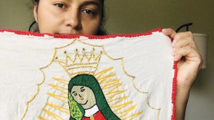 Irene, an asylum seeker, holds up an embroidery she made as part of Artisans Beyond Borders. 