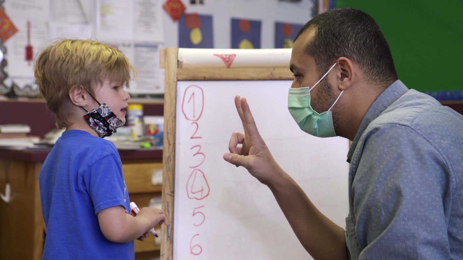 A masked teacher offers instruction to a student at the International School of Tucson. February 2021. 