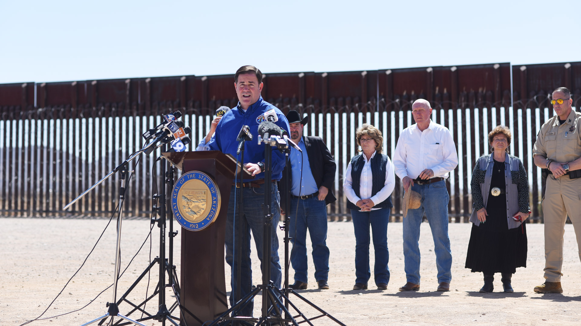 Governor Doug Ducey addresses members of the media in front of a portion of border wall near the Douglas Municipal Airport on March 19, 2021.