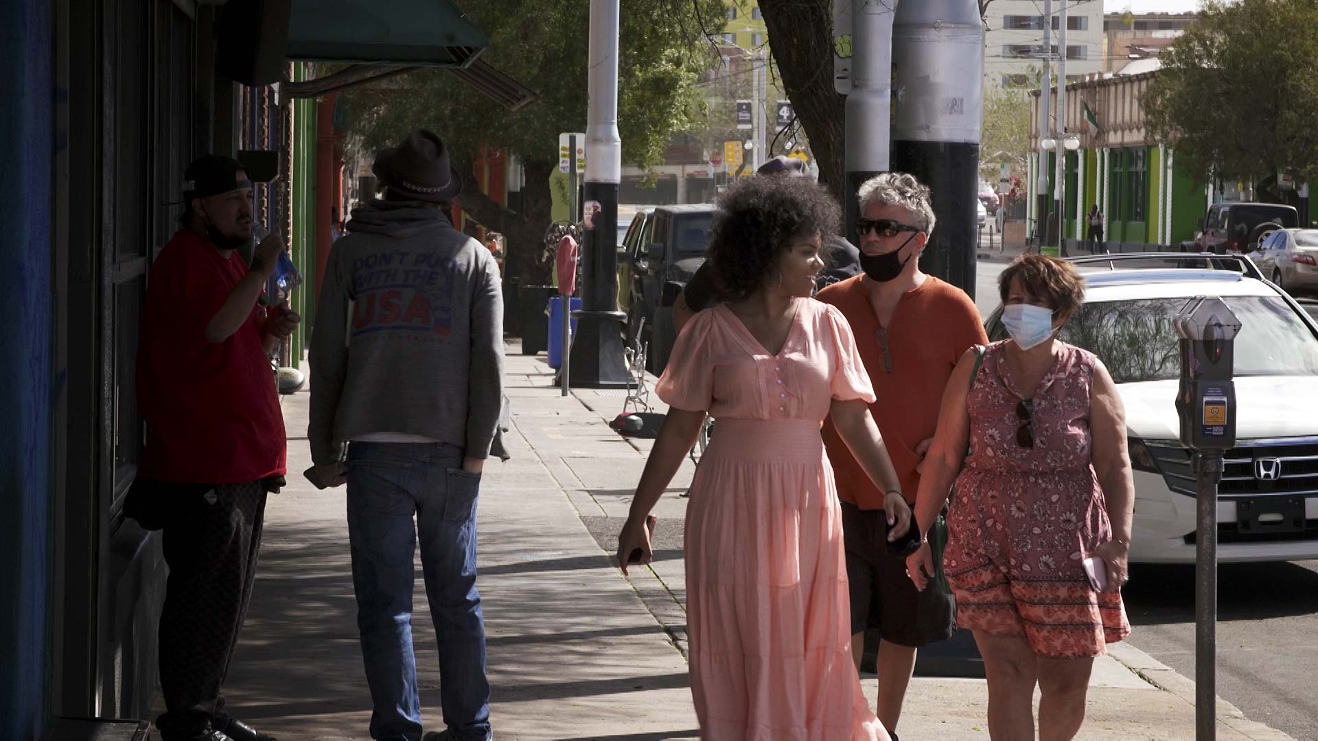 A woman walks down 4th Avenue maskless. Others around her are wearing face coverings. March 2021. 