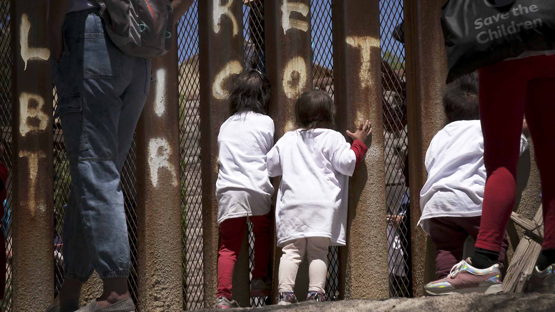 Children peer through the border fence in Nogales, Sonora during a march led by migrants on April 30, 2021 who wanted to call attention to immigration policies in the United States that have prevented them from entering the country while they seek political asylum. 