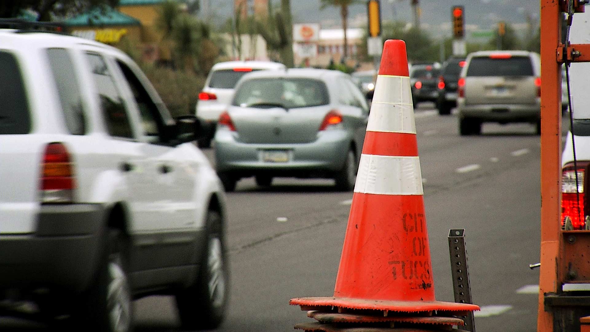 A traffic cone along Speedway Boulevard as traffic passes in the background. 