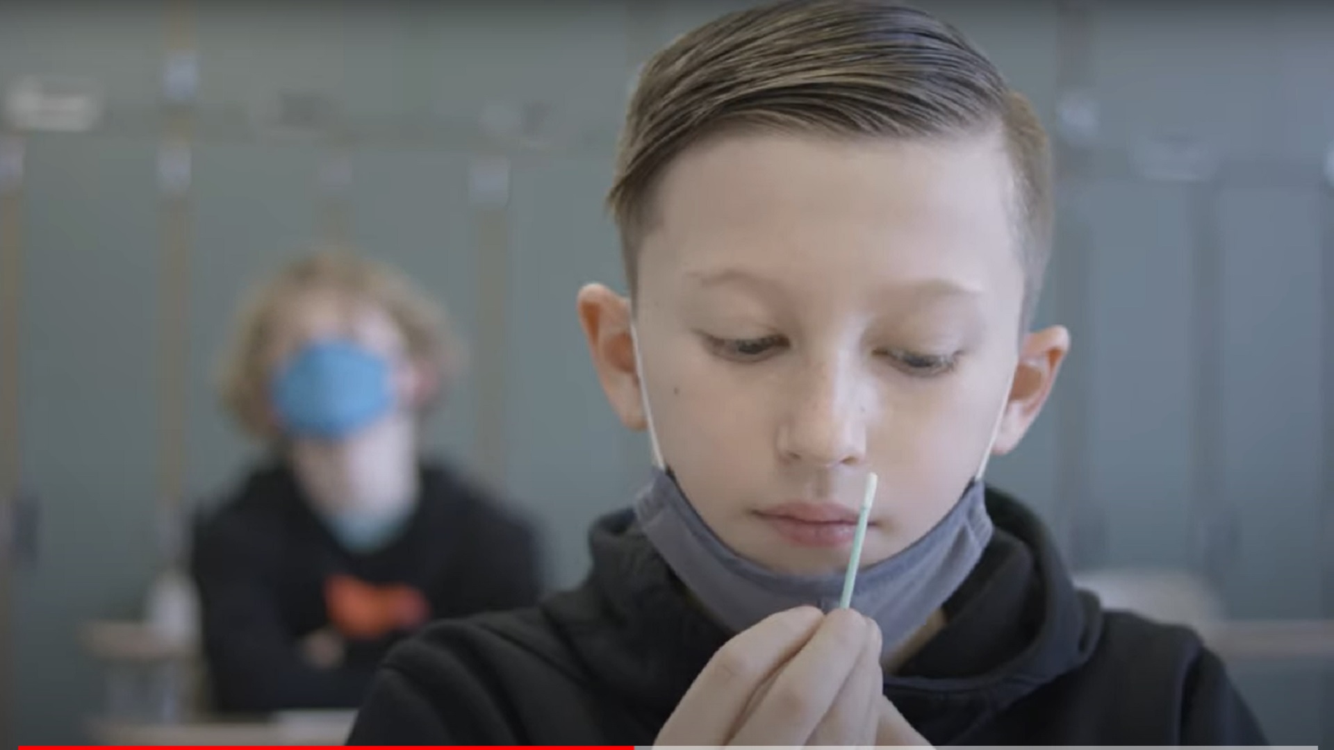 An elementary school student prepares to self-administer a COVID-19 test in a frame from a promotional video by Ginkgo Bioworks, which distributes "pooled testing" systems to schools around the country. 