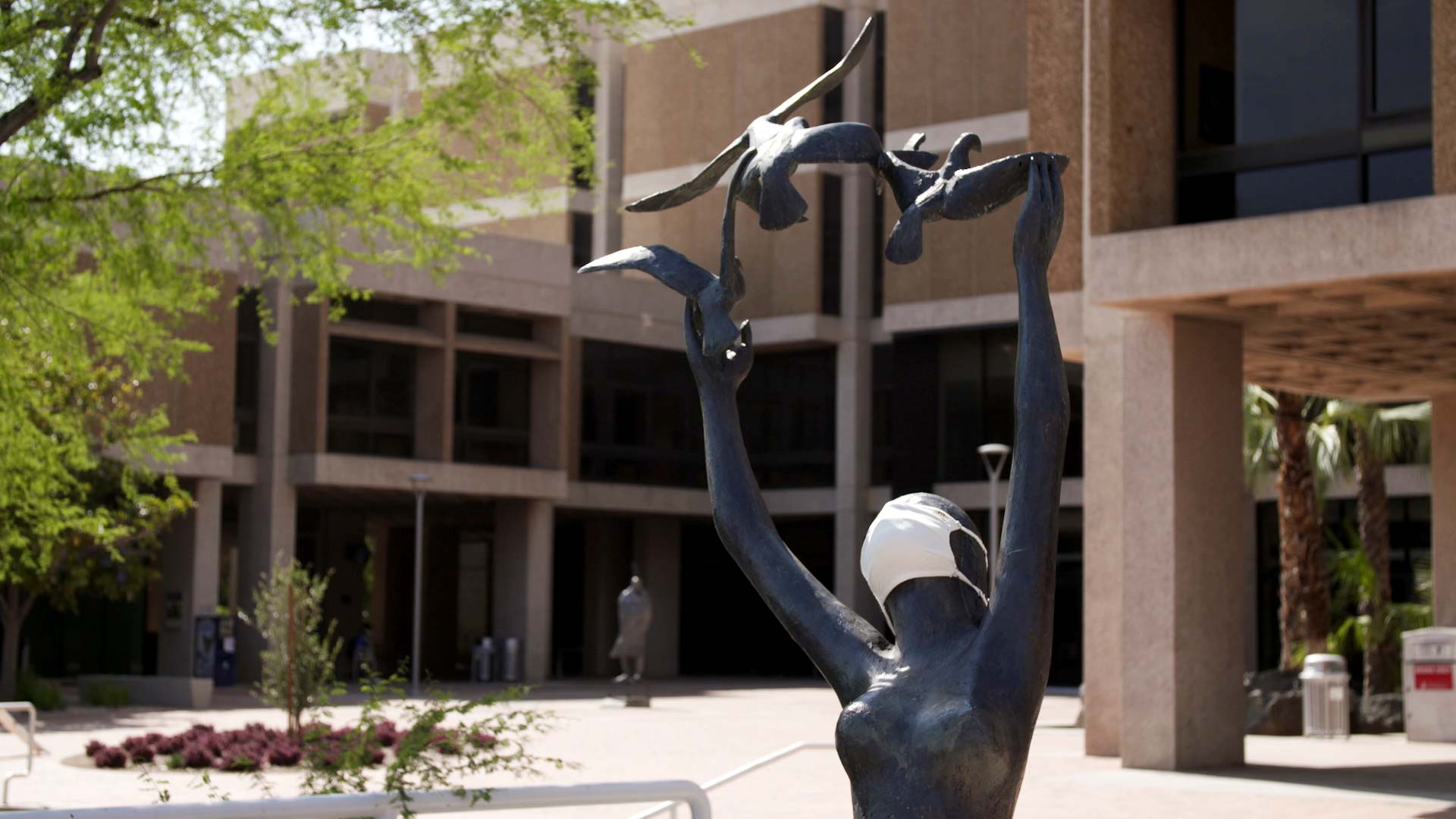 A sculpture outside of the University of Arizona's Main Library is donned with a face mask. 