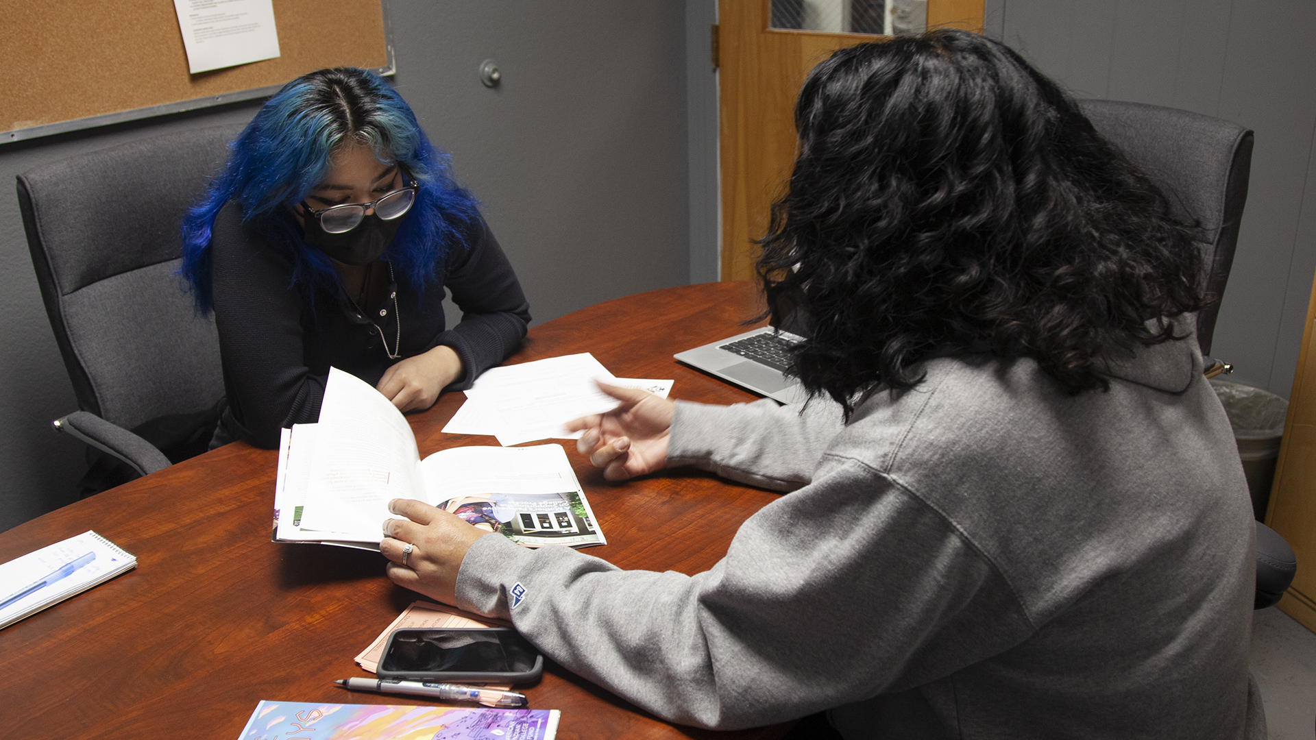 Mya Yazzie, a Diné 17-year-old senior at Sunnyside High School, looks at an Indigenous focused college guidebook with Felisia Tagaban Gaskin, a Diné UA and Sunnyside Unified School District employee supporting Indigenous high schoolers in higher education.