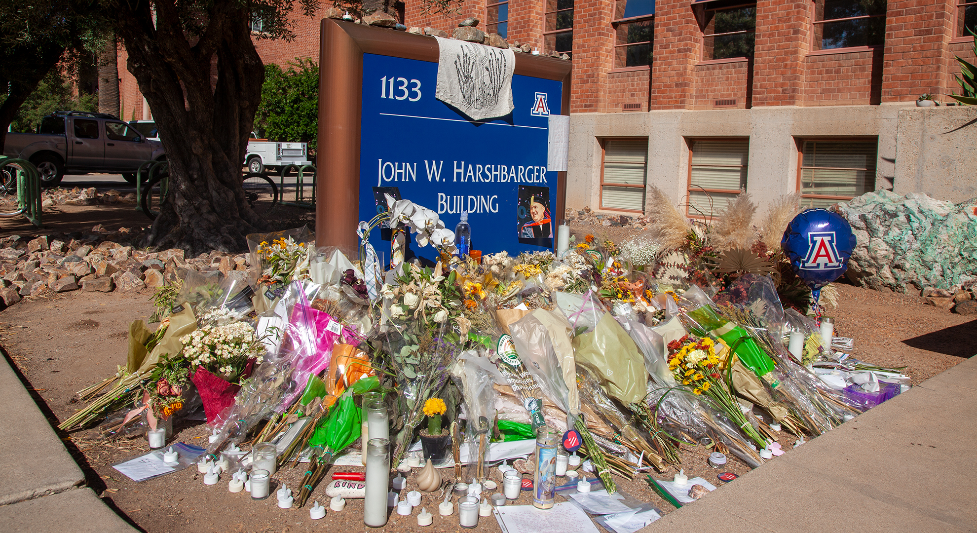 Flowers, candles and letters lay in front of the Harshbarger building sign following the murder of Professor Thomas Meixner on Wed. Oct. 5, 2022 at the University of Arizona. Meixner was killed by a former student on campus.