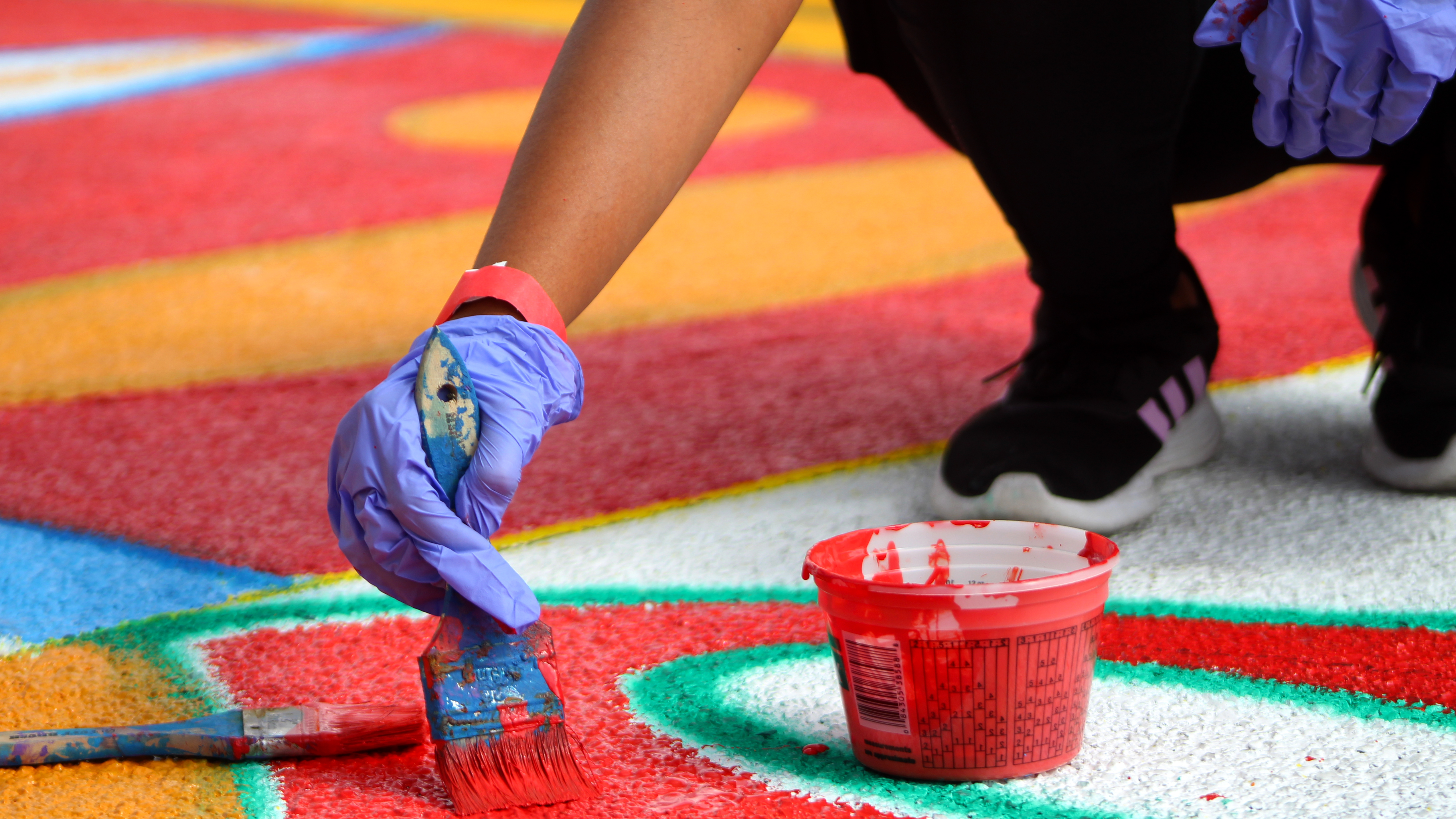 A volunteer is painting a section of a new mural that is being installed onto 6th avenue on Saturday, Oct. 22, 2022 at a high traffic street near Armory Park and the Children's Museum. At around 11:30 a.m., red paint started to run out and organizers were trying to find more. 