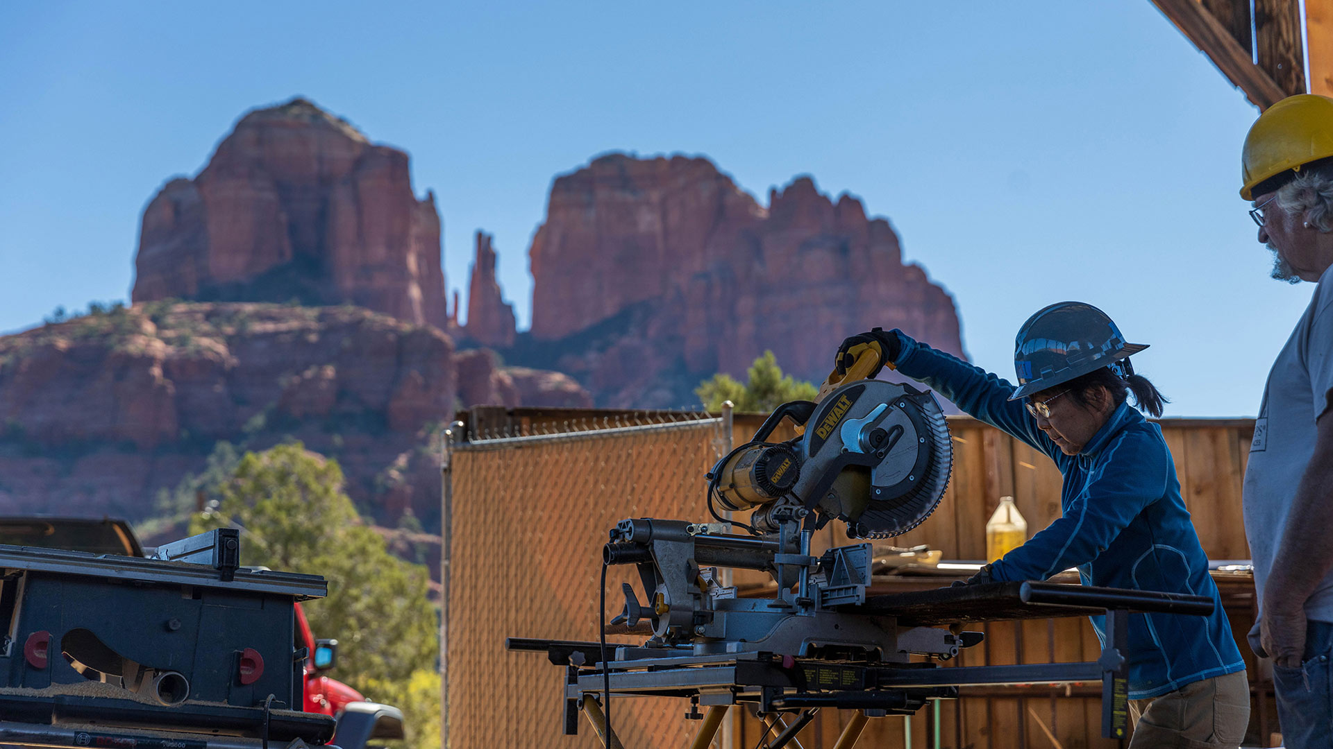 HistoriCorps volunteer Yumi Shimizu, left, learns how to use a circular saw from project supervisor Pete Specht in 2022 with Sedona’s Cathedral Rock as a picturesque backdrop. 