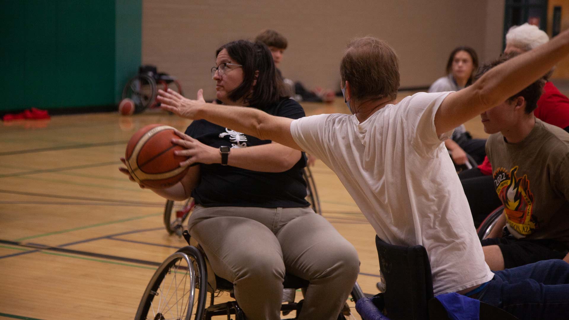 A woman is attempting to pass a basketball to someone behind her as an attendee blocks her shot.
