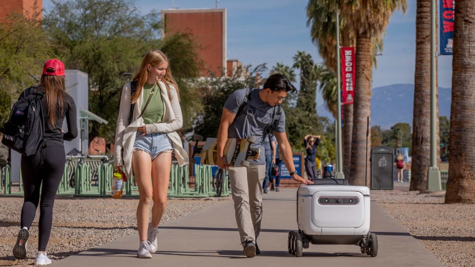 University of Arizona students interact with an autonomous food delivery "robot" operated by Grubhub and supplied by the Russian conglomerate Yandex.