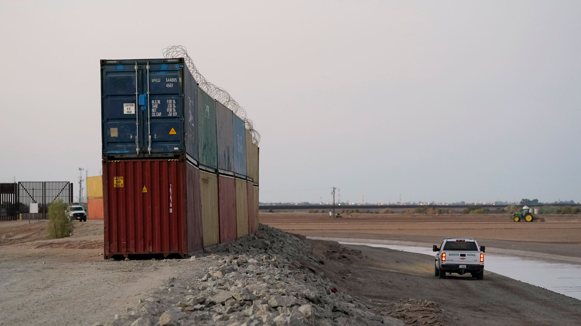 Border Patrol agents patrol along a line of shipping containers stacked near the border Tuesday, Aug. 23, 2022, near Yuma, Ariz. 