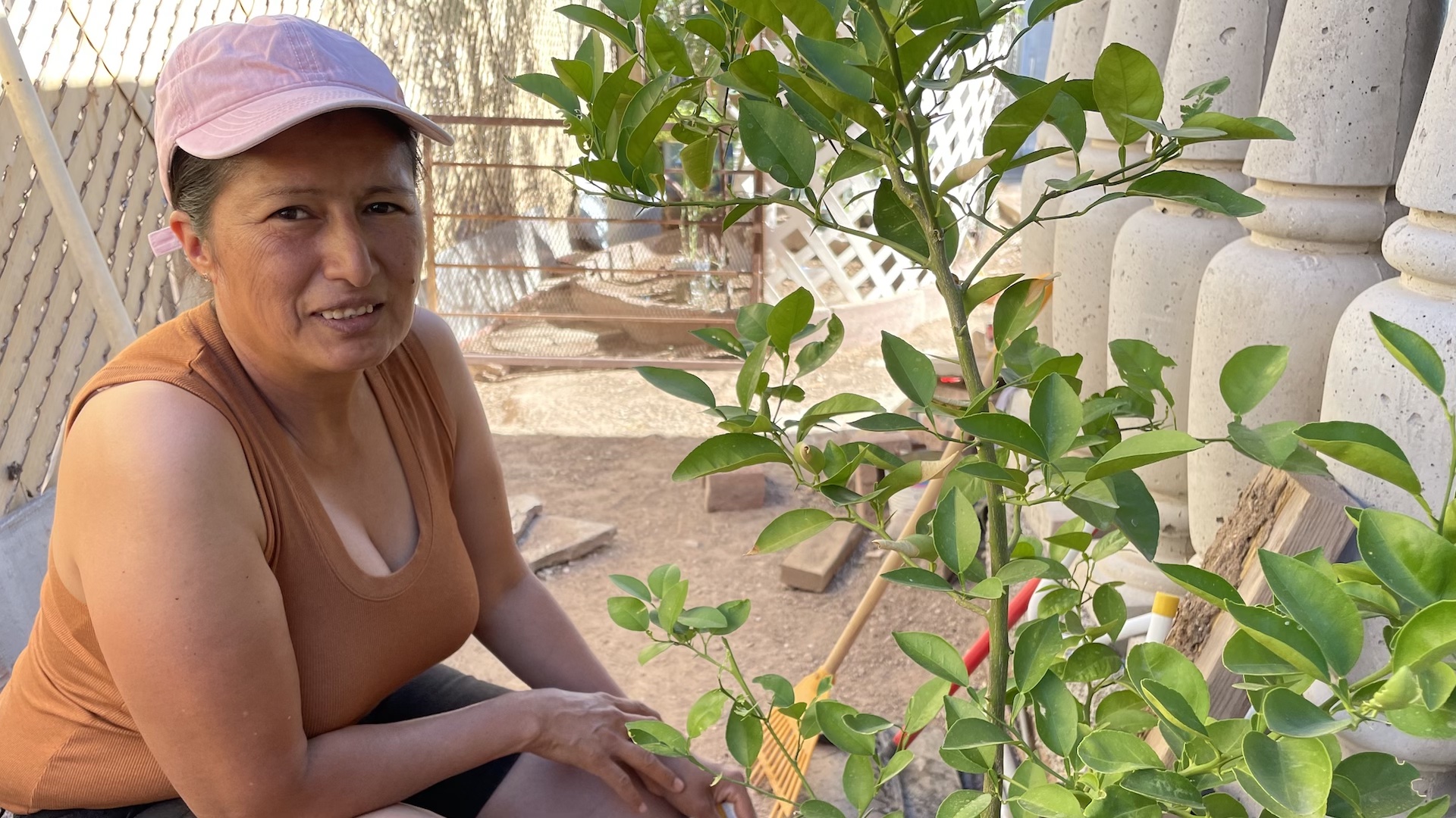 Raquel Fregoso in her Tucson garden. The organization SERI installed her rainwater harvesting system, which includes a big, green cistern on the side of her house.
