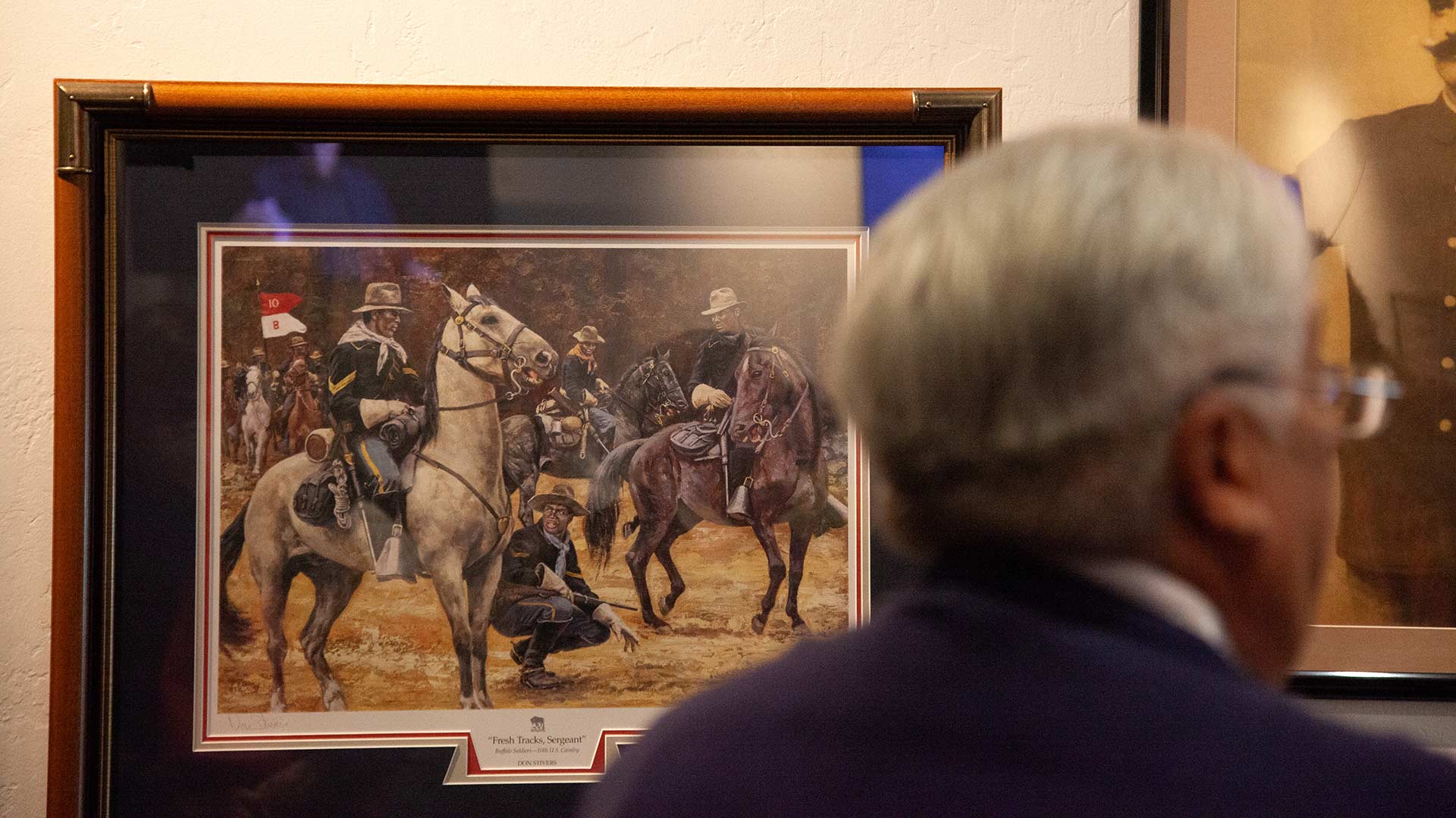 An attendee stands in front of artwork depicting the Arizona Buffalo Soldiers at the African American Museum of Southern Arizona on Saturday, Jan. 14 2023. The African American servicemen in the painting were allowed to join the U.S. Army in 1866. 