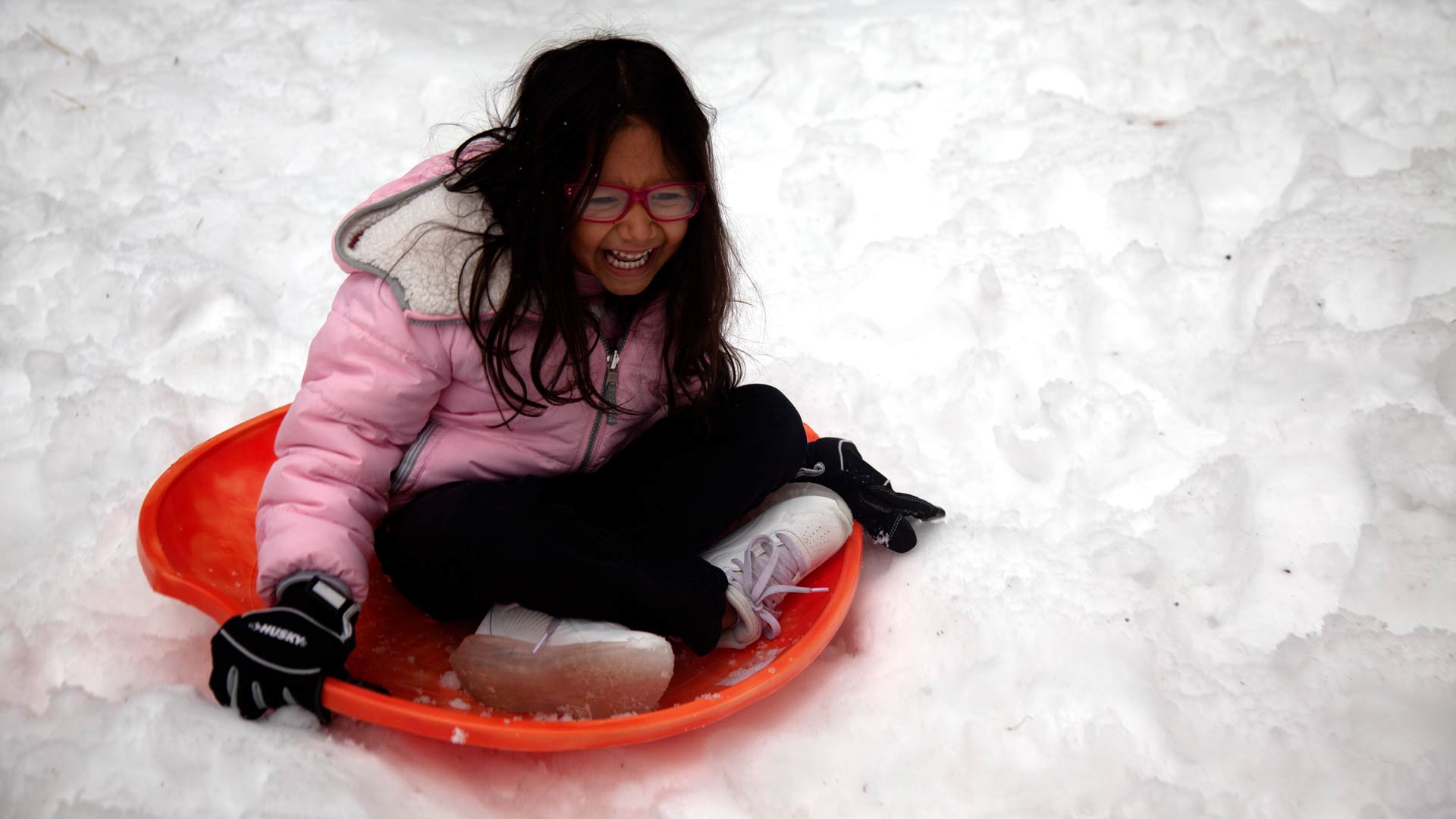 Girl sledding in snow on Mount Lemmon