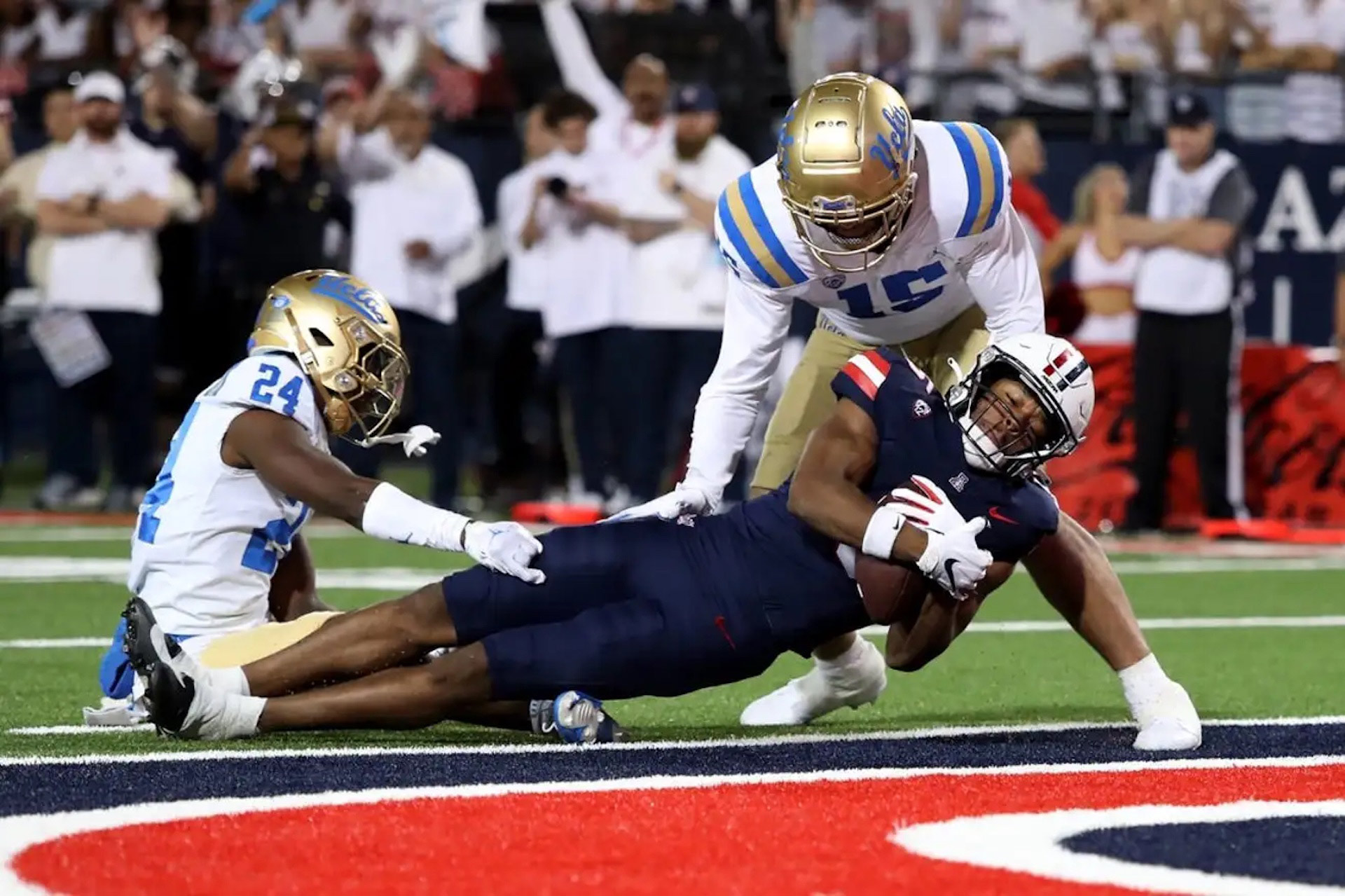 Arizona wide receiver Montana Lemonious-Craig scores a touchdown against UCLA defensive back Jaylin Davies and defensive lineman Laiatu Latu during the first half of an NCAA college football game Saturday, Nov. 4, 2023, in Tucson, Ariz. 