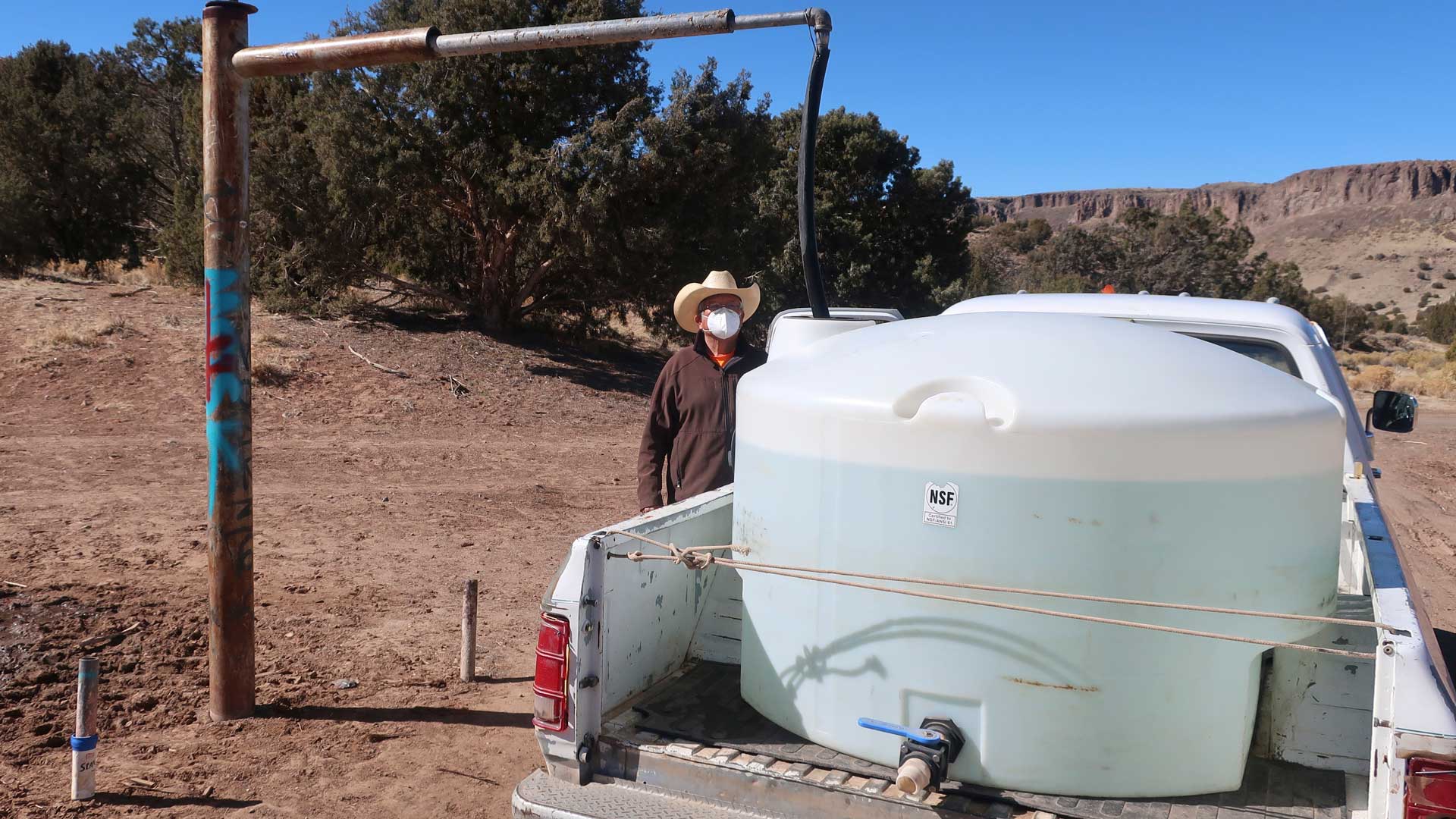 Phillip Yazzie waits for a water drum in the back of his pickup truck to be filled in Teesto, Ariz., on the Navajo Nation, on Feb. 11, 2021.  