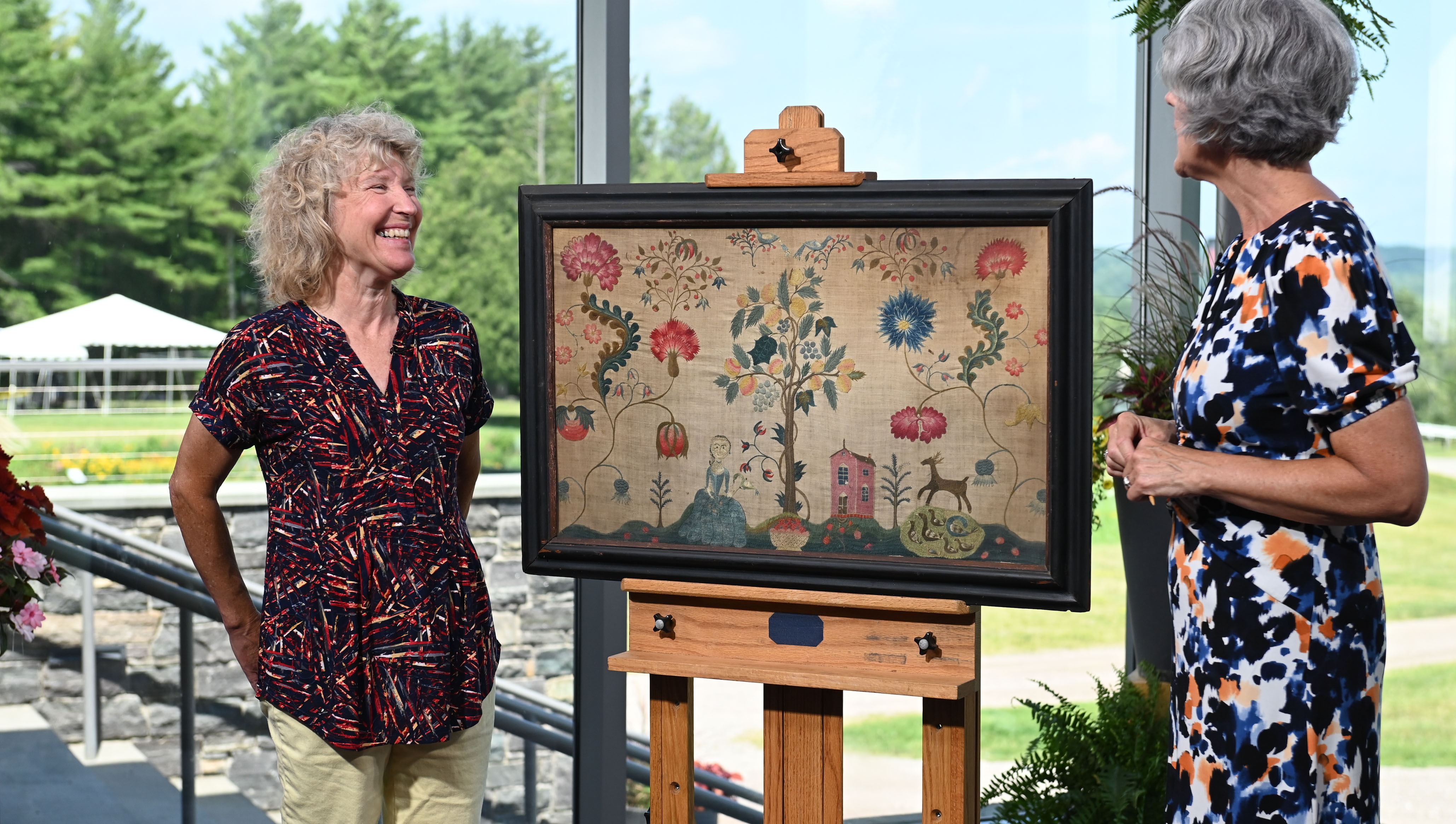 Deborah Miller (right) appraises a schoolgirl needlework, ca. 1740, in Shelburne, VT. 